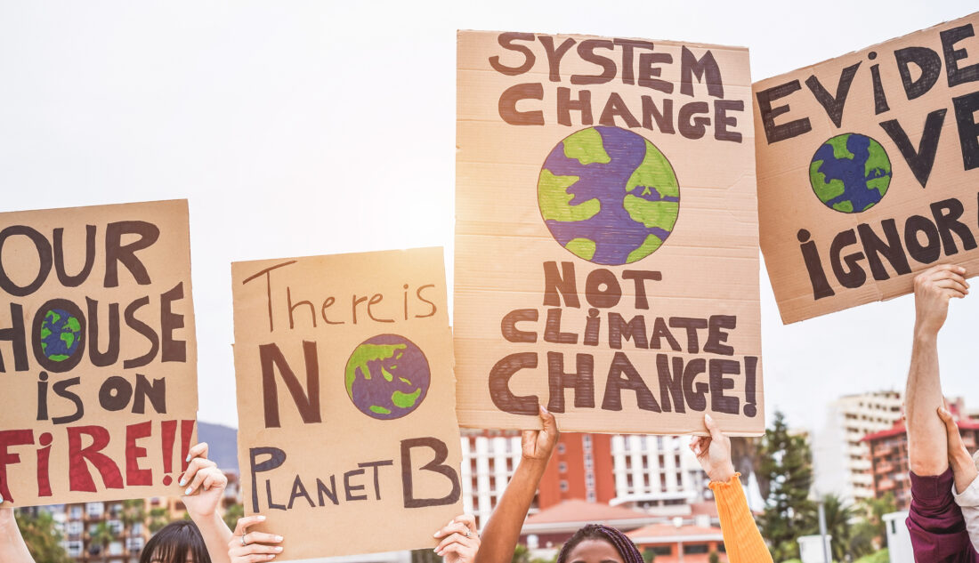 People holding cardboard signs above their head with messages aboug climate change