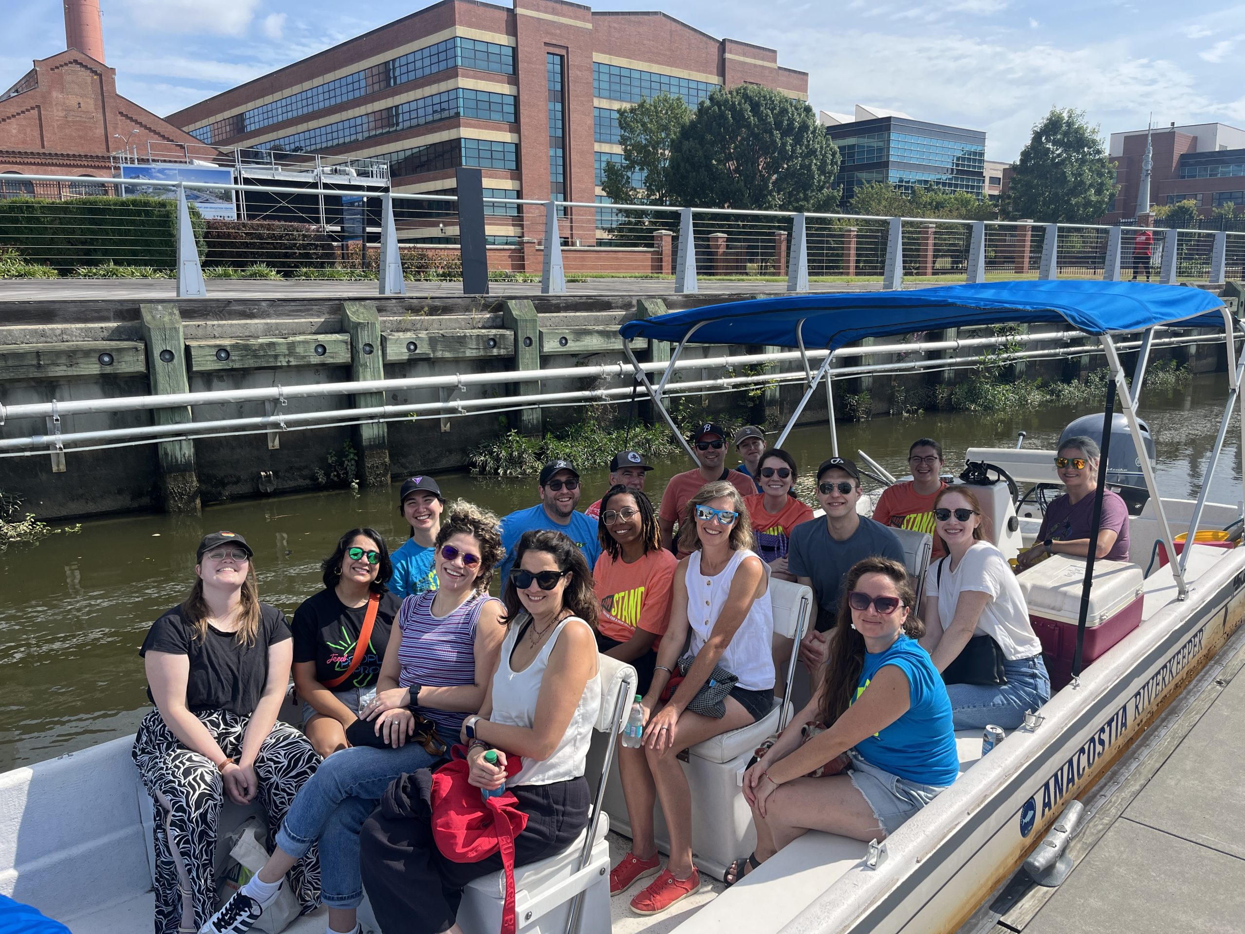 FarmSTAND staff on a motor boat that says "Anacostia Riverkeeper" on the side.